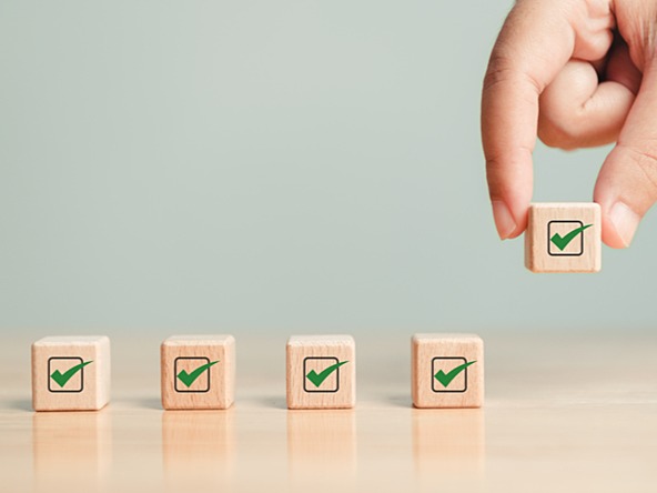 wooden blocks with a green tick, one being picked up by a hand